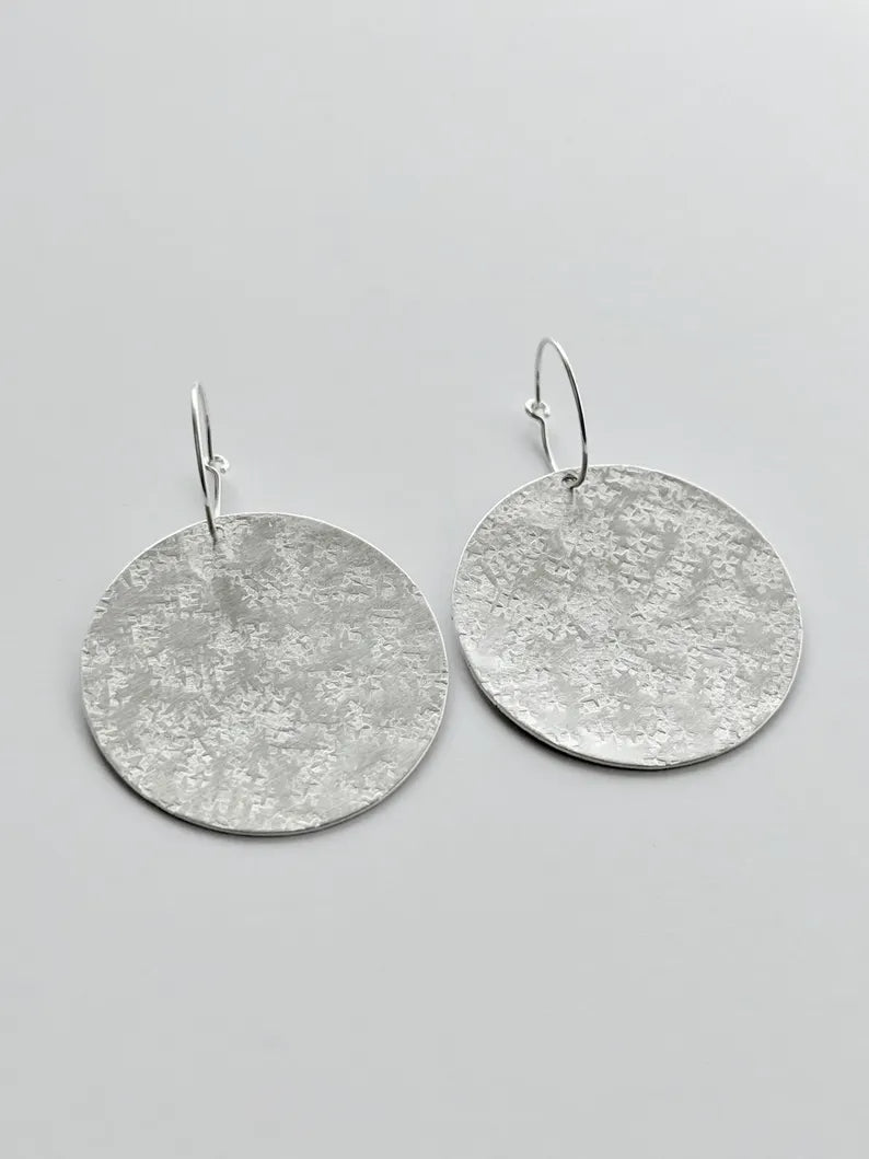 Large sterling silver textured disc hoop earrings.