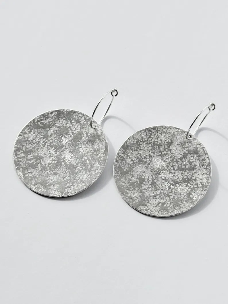 Large sterling silver textured disc hoop earrings.