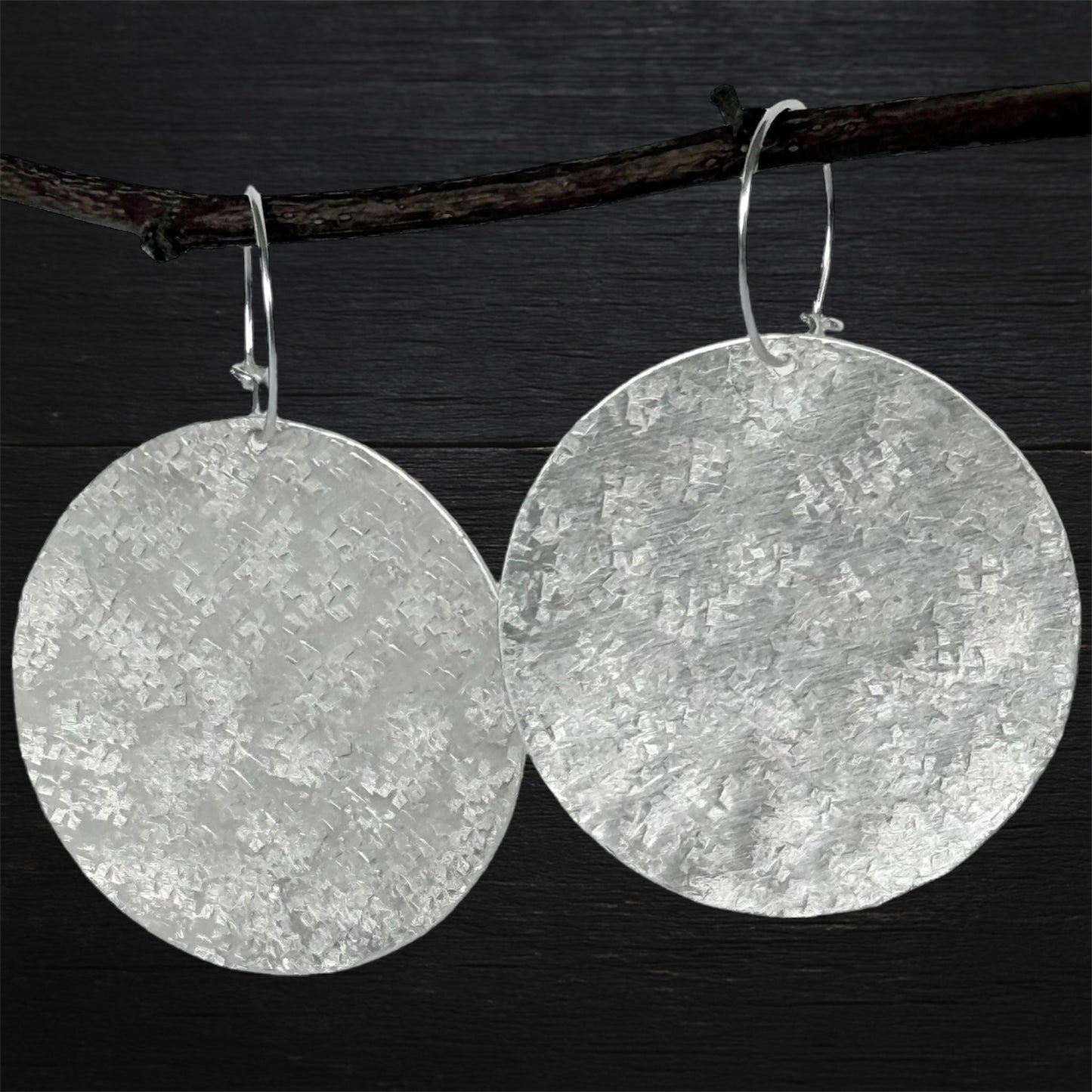 Large sterling silver textured disc hoop earrings.