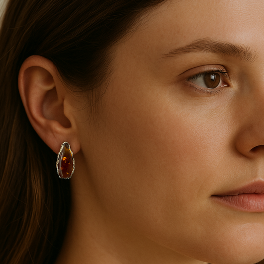 Close-up of a woman wearing a sterling silver stud earring with a brown baltic amber.