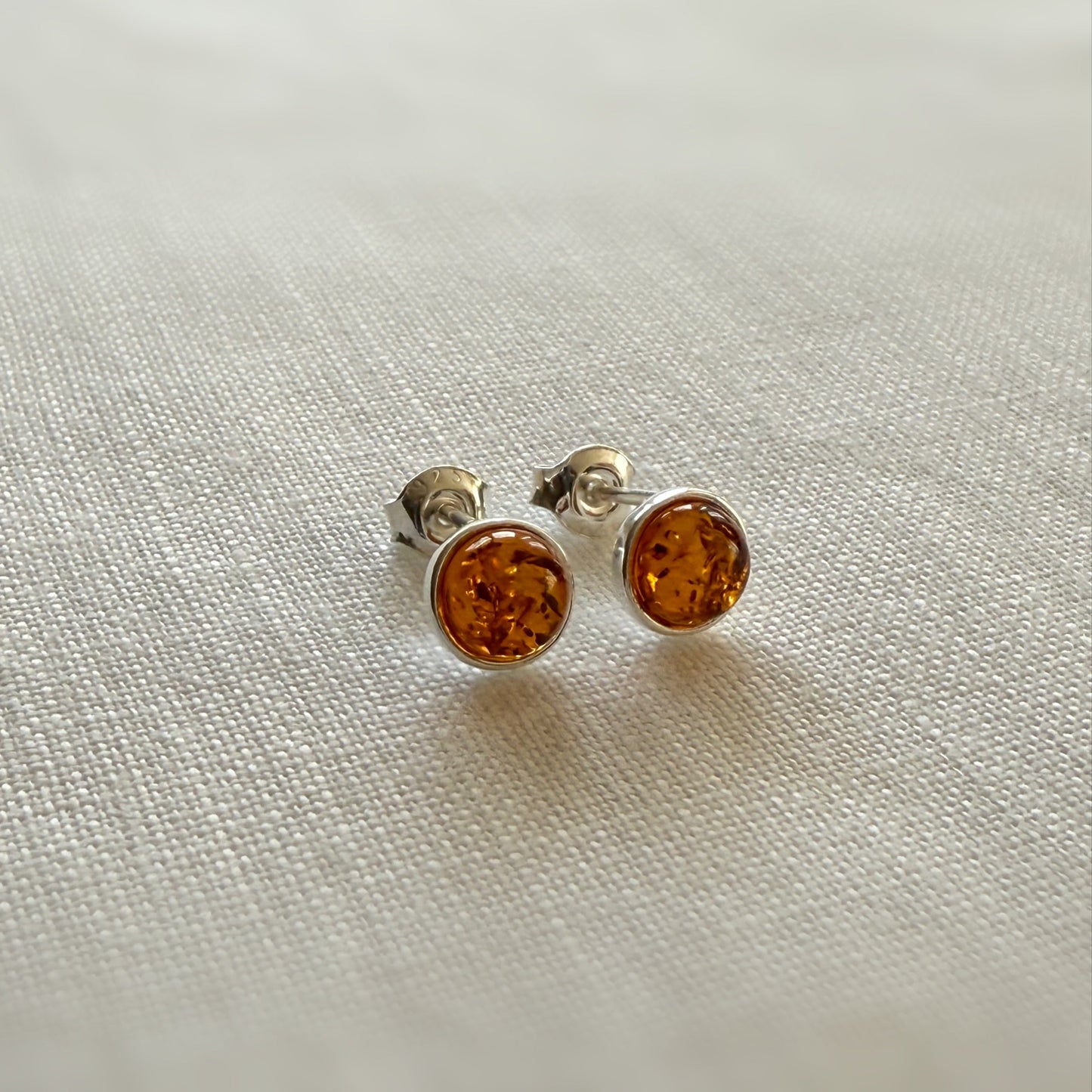 Pair of amber stud earrings on a light fabric background