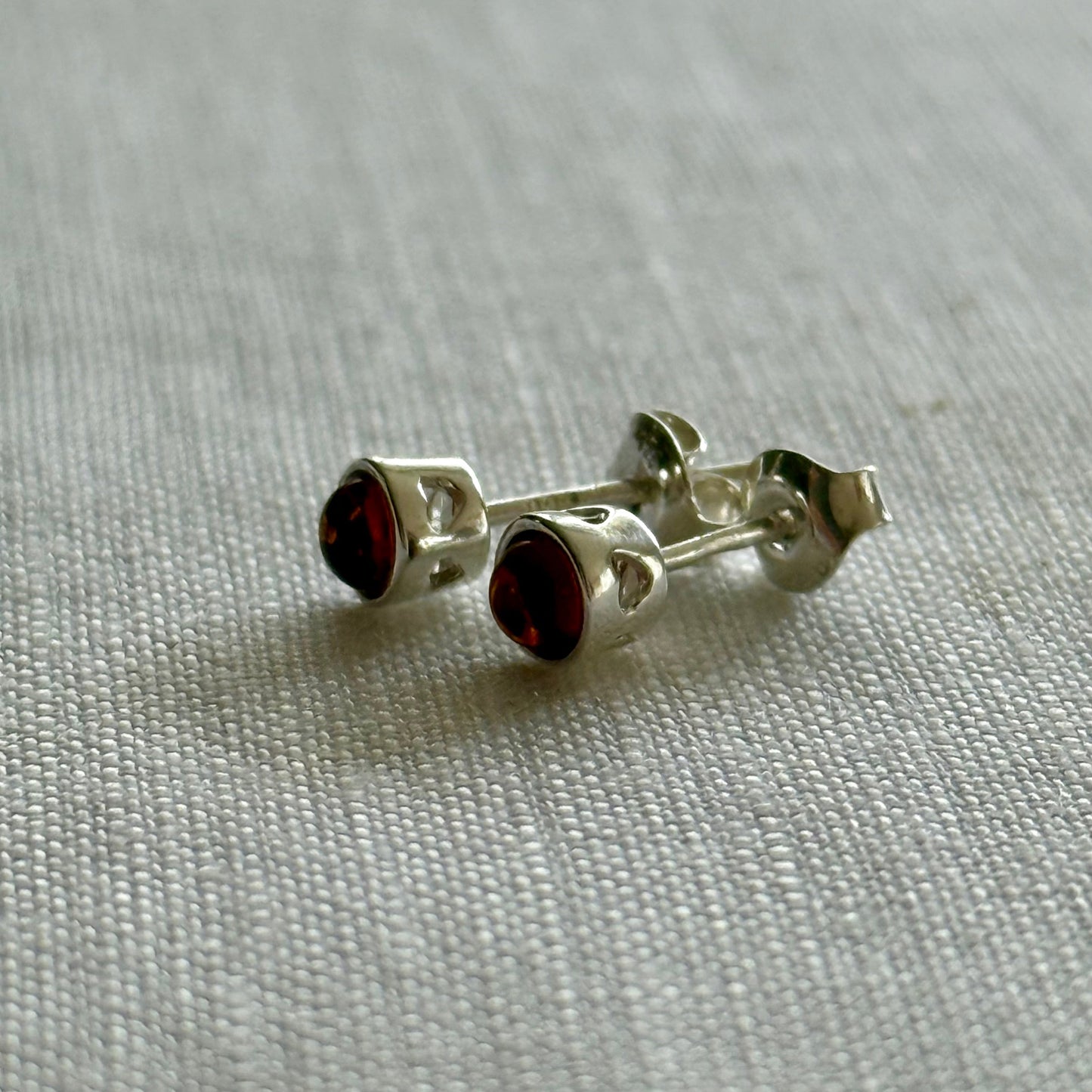 Silver earrings with amber gemstones on a light gray fabric background