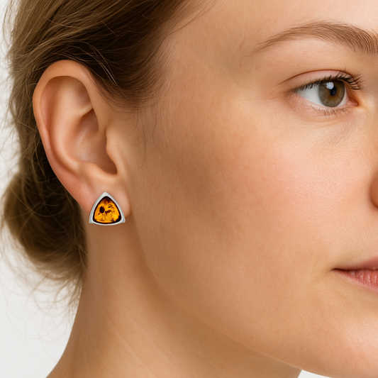Close-up of a woman wearing a triangular stud earrings with a genuine Baltic Amber set in Sterling Silver