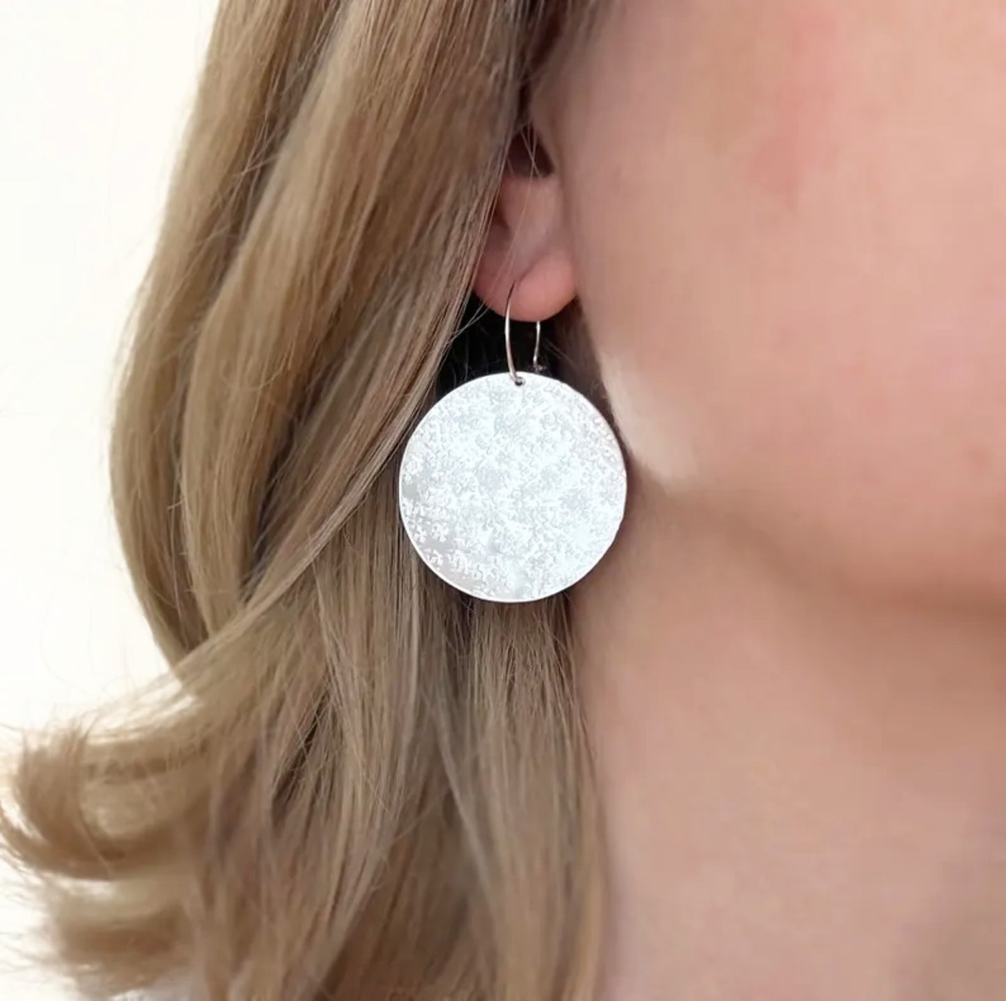 Large sterling silver textured disc hoop earrings.