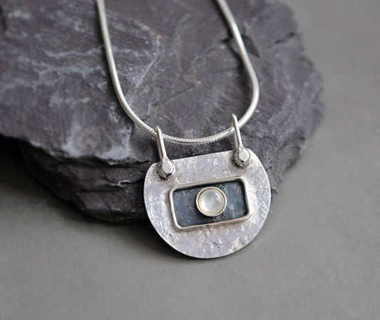 Handmade sterling silver artisan necklace with textured and partially oxidised pendant featuring a natural Mother of Pearl, hanging from a sleek sterling silver snake chain.