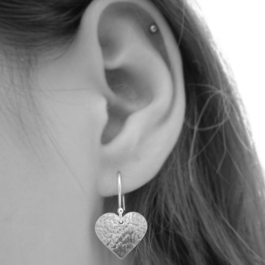 Sterling silver hammered heart dangle earrings.