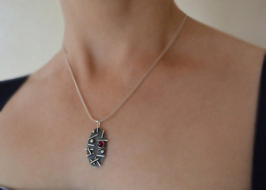 Garnet oxidised sterling silver oval necklace.