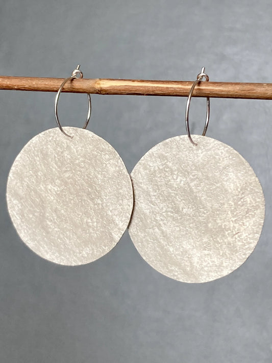 Large sterling silver textured disc hoop earrings.