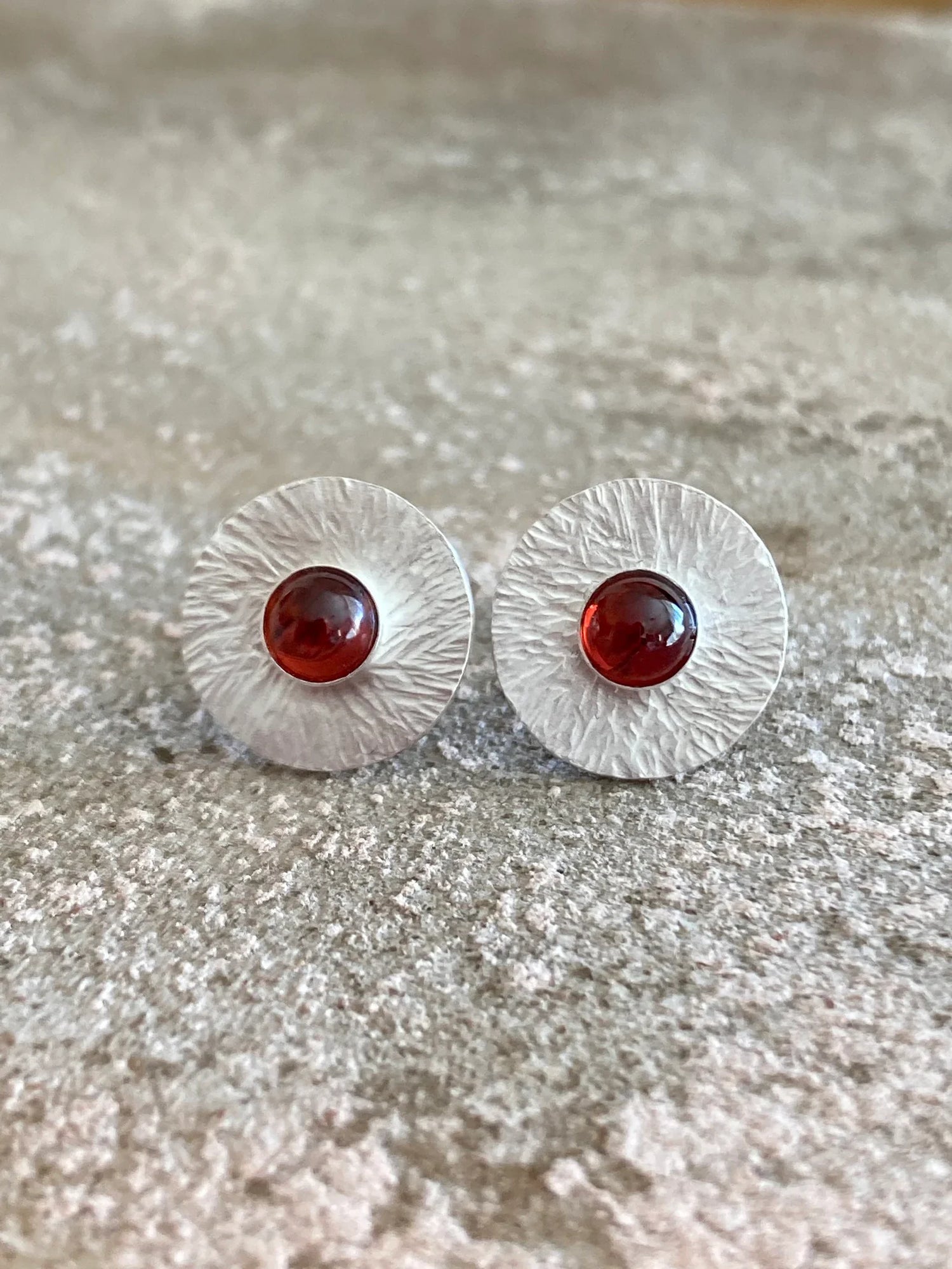 Sterling silver textured disc stud earrings featuring a natural garnet