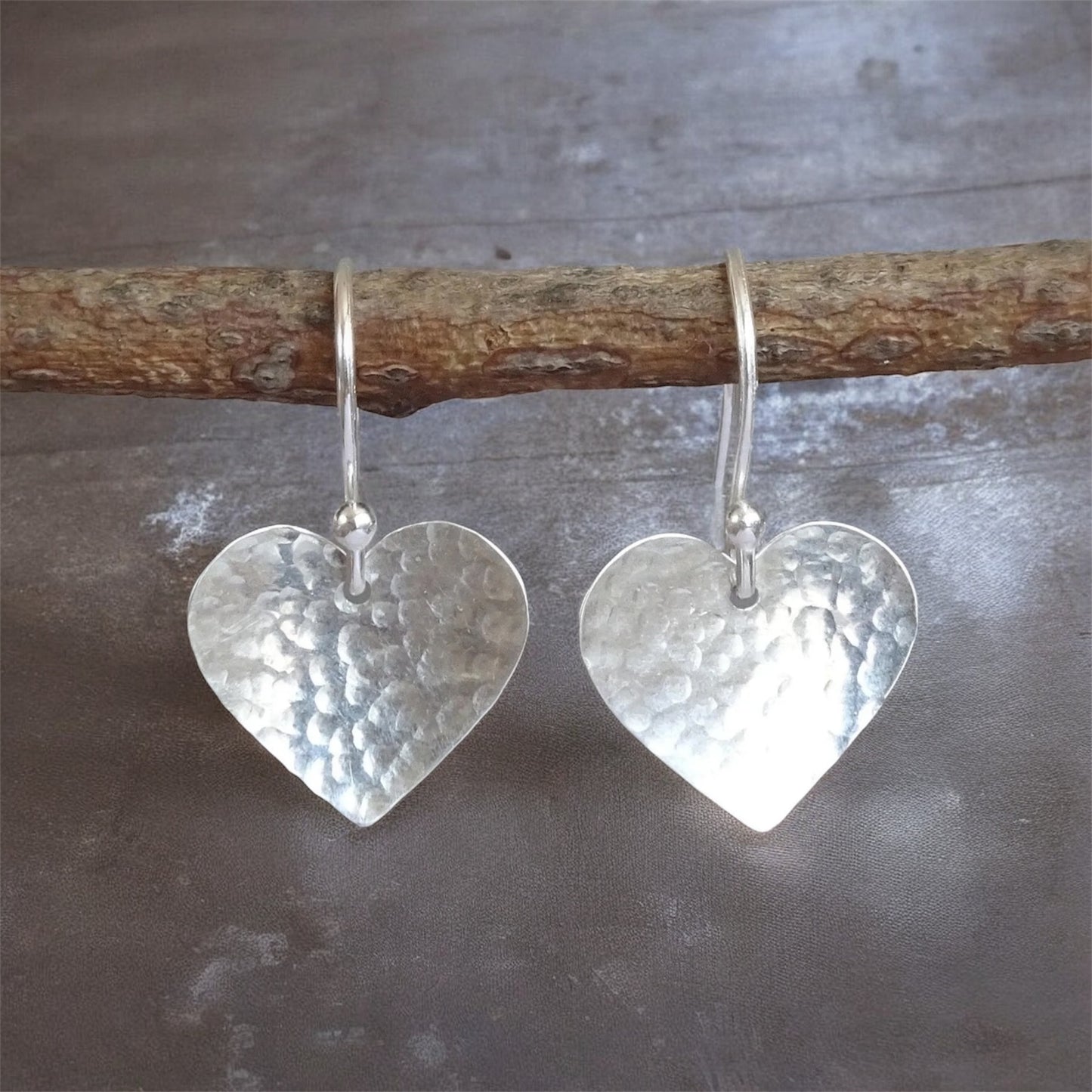 Sterling silver hammered heart dangle earrings.