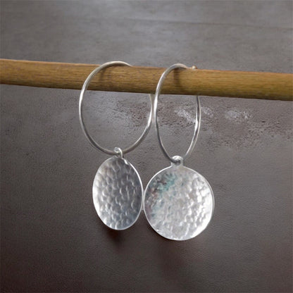 Hammered sterling silver disc hoop earrings.