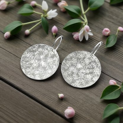 Large sterling silver textured disc hoop earrings.