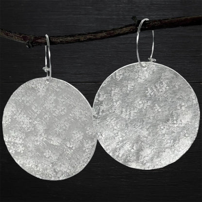 Large sterling silver textured disc hoop earrings.