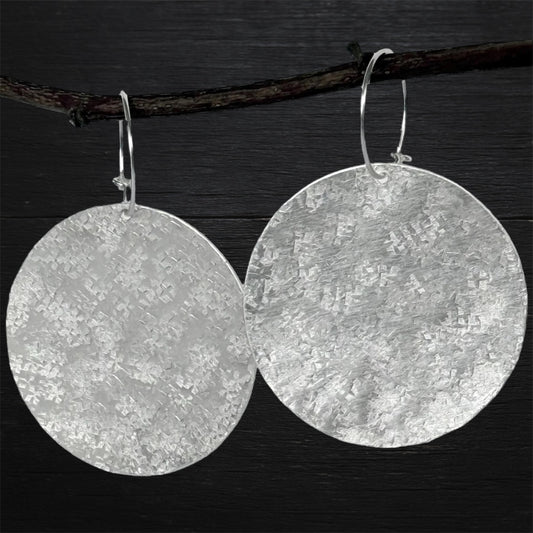 Large sterling silver textured disc hoop earrings.