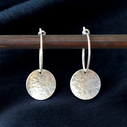 Sterling silver hammered disc hoop earrings.