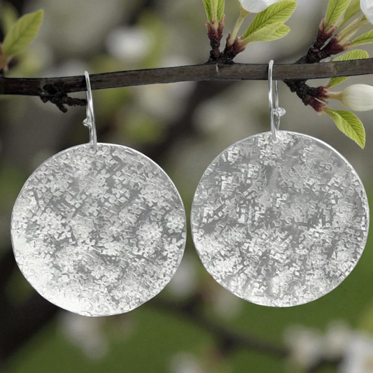 Large sterling silver textured disc hoop earrings.