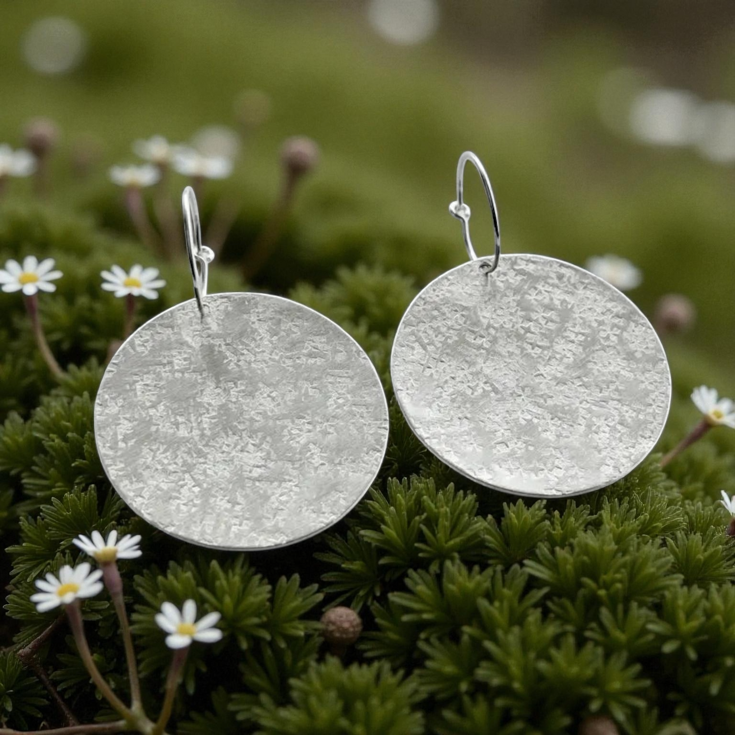 Large sterling silver textured disc hoop earrings.