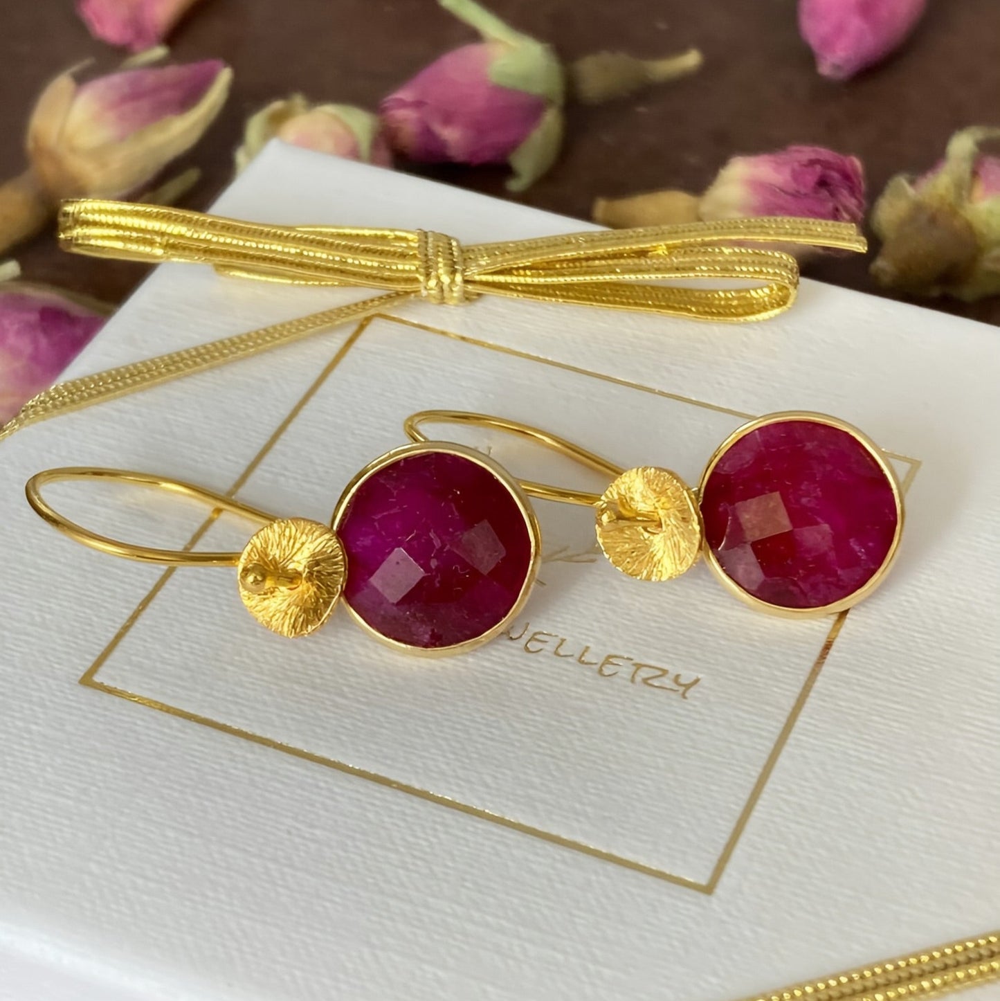 Faceted ruby dangle earrings in 24k gold vermeil, displayed on a Kaila Jewellery branded gift box with decorative ribbon.