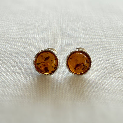 Pair of amber and sterling silver stud earrings on a light fabric background