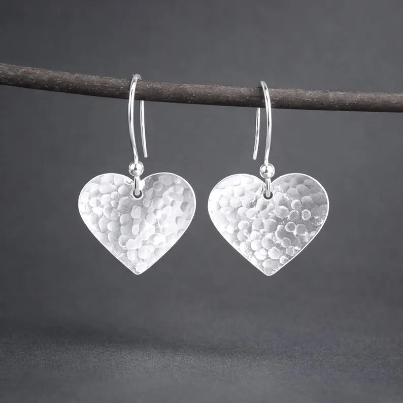 Sterling silver hammered heart dangle earrings.