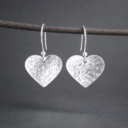 Sterling silver hammered heart dangle earrings.