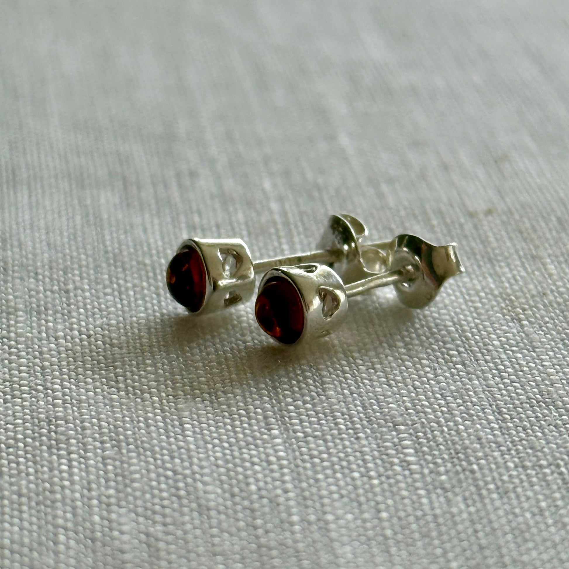 Silver earrings with amber gemstones on a light gray fabric background