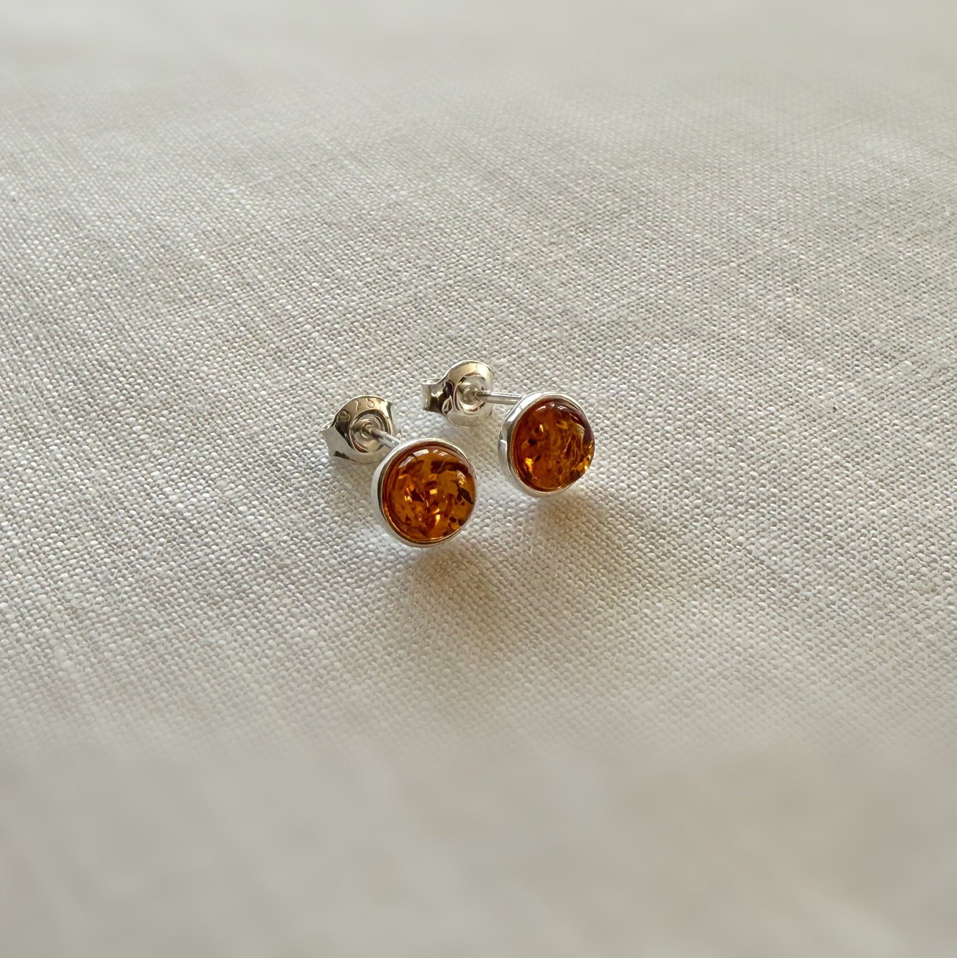 Pair of amber stud earrings on a light fabric background