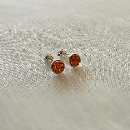 Pair of amber stud earrings on a light fabric background