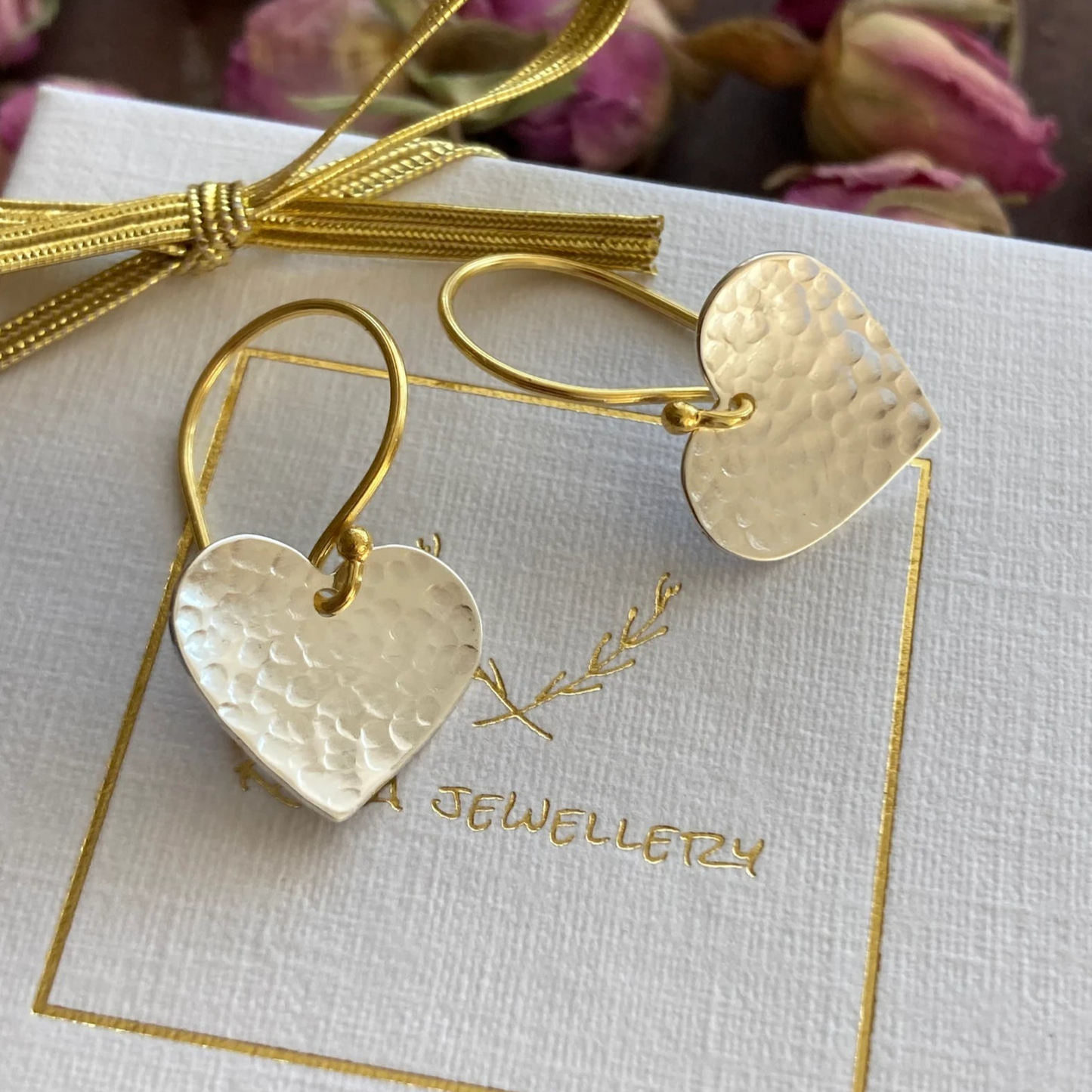 Silver and gold textured heart dangle earrings.