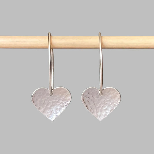 Sterling silver dangle heart earrings featuring a hammered heart suspended from a v shape ear wire