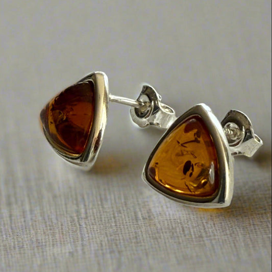 Pair of genuine baltic amber triangle earrings with silver settings on a textured white background