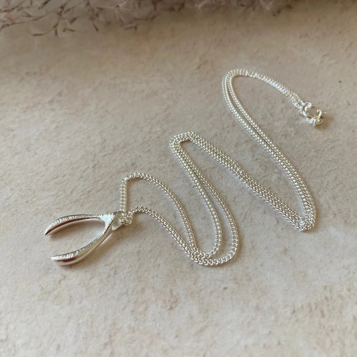 sterling silver textured wishbone necklace suspended from a sterling silver curb chain